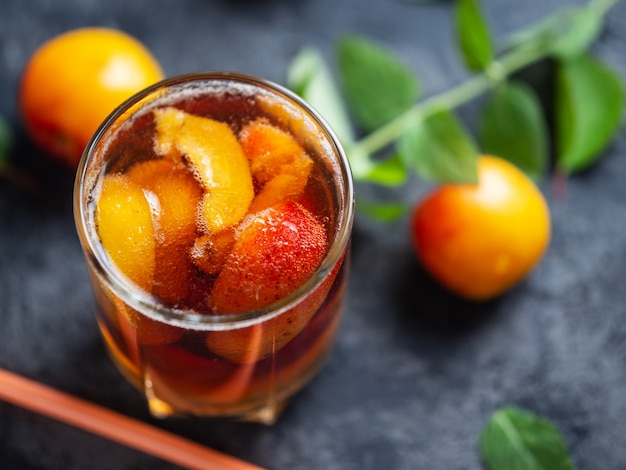 Cocktail de boisson d'abricot d'été avec ou sans alcool à la menthe et morceaux de fruits en gros plan