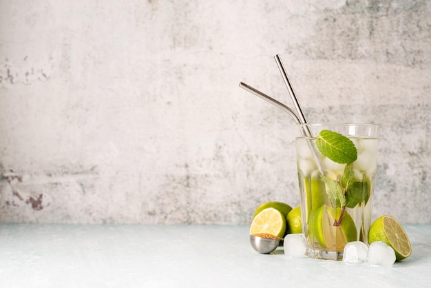 Cocktail de caipirinha d'été frais sur fond de béton avec citron vert sur table