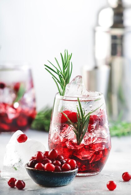 Cocktail de canneberges d'hiver avec du jus de glace à la vodka, du romarin et des baies rouges Long drink festif Fond de table gris avec espace négatif