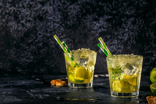 Cocktail de citron vert frais avec de la glace sur fond sombre.