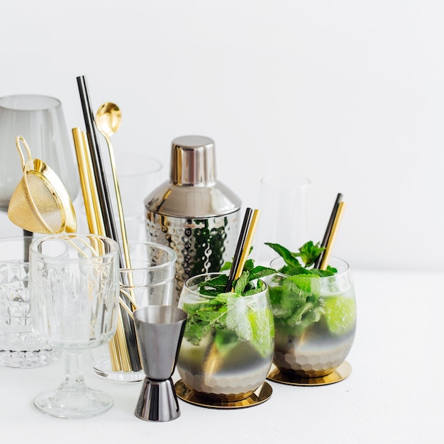 Cocktail avec citron vert, menthe et glace et accessoires de bar. Boissons d'été.