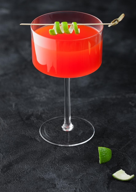 Cocktail cosmopolite dans un verre de cristal moderne avec zeste de citron vert sur fond de tableau noir Vue de dessus