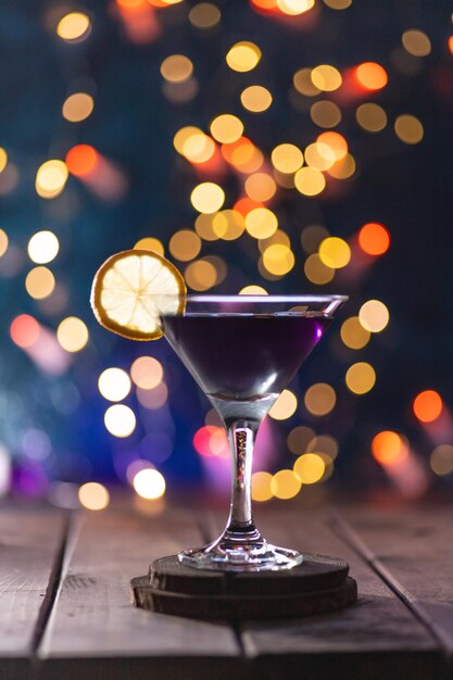 Cocktail dans un verre triangulaire sur fond de lumières Un verre sur le bar