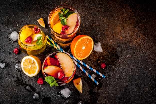 Photo cocktail d'été froid composé de trois fruits et boisson sangria aux baies. rouge blanc rose avec pommes oranges citron et framboise