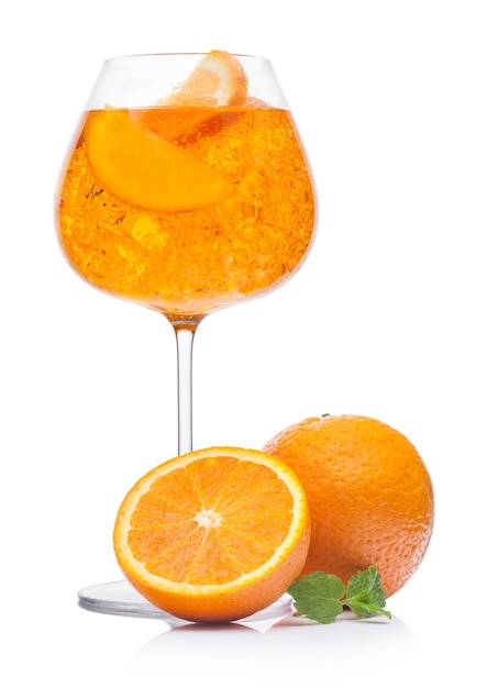 Cocktail d'été Spritz avec glace et tranche d'orange dans un verre à vin sur fond blanc avec des oranges fraîches et des feuilles de menthe