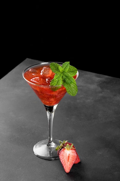 Cocktail de fraises d'été froid mojito margarita daiquiri dans un verre à martini sur fond noir gros plan