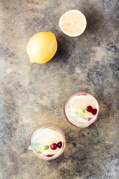 Cocktail froid rafraîchissant d'été avec du citron, de la mélisse et de la cerise - seltzer dur dans des verres sur la table