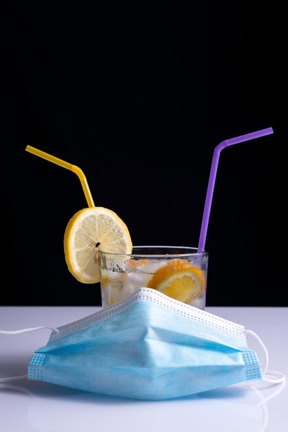 Photo cocktail fruité de coronavirus dans le concept de masque de protection sur table blanche et fond noir