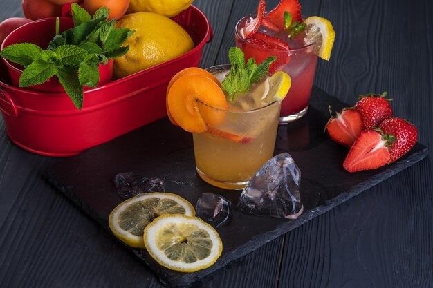 Cocktail De Fruits Avec Fruits Frais Et Glace. Dans Des Verres Sur Fond De Bois Noir Rustique