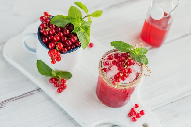 Cocktail de fruits rafraîchissant ou punch maison avec champagne, groseille rouge, glaçons et feuilles de menthe