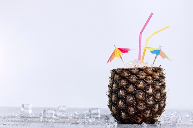 Cocktail de fruits tropicaux à l'ananas avec de la glace sur une assiette blanche. La glace fond sur la table de marbre. Vacances