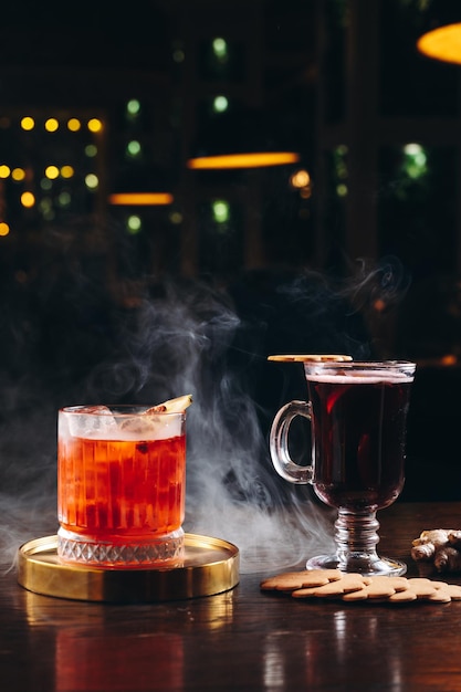 Cocktail fumé à l'ancienne et vin chaud sur la table sur fond sombre