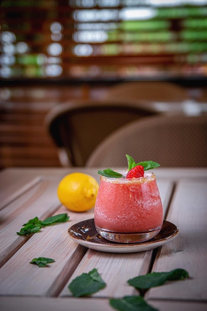 Cocktail gin tonic rafraîchissant alcoolisé avec smoothie aux fraises et menthe avec des glaçons sur la terrasse d'été du restaurant Strawberry Daykiri