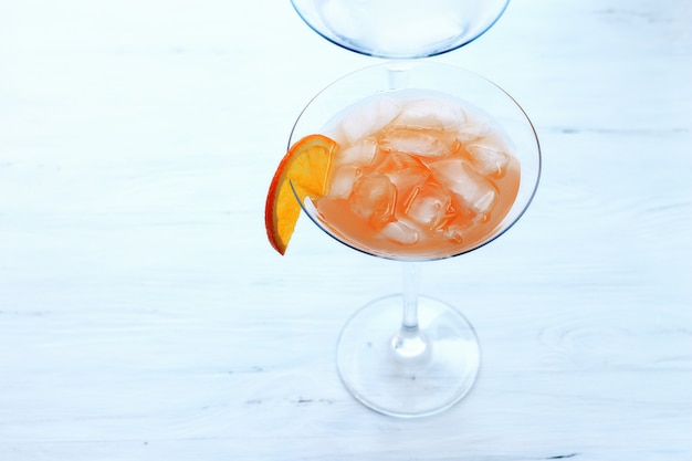 cocktail avec de la glace dans un verre au bord d&#39;un verre de vue de dessus de fond orange clair