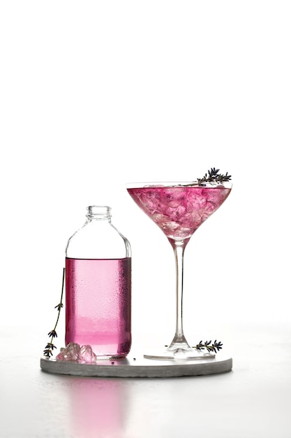 Cocktail glacé à la lavande Boisson froide violette dans un verre et une bouteille sur tableau blanc et fond blanc
