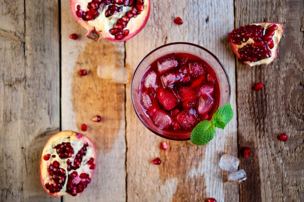 Cocktail à la grenade avec de la menthe glacée et des fruits sur une table en bois. Boisson d'été rafraîchissante douce ou alcoolisée. Vue de dessus à plat