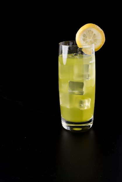 Cocktail jaune avec glace, tranche de citron sur fond noir