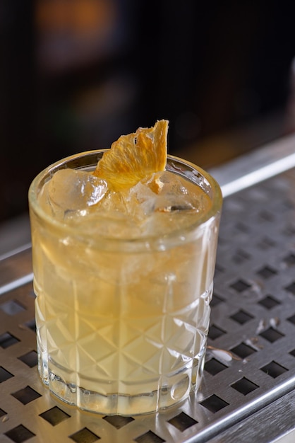Cocktail jaune vif prêt à l'emploi avec des agrumes dans un verre à l'ancienne sur le bar