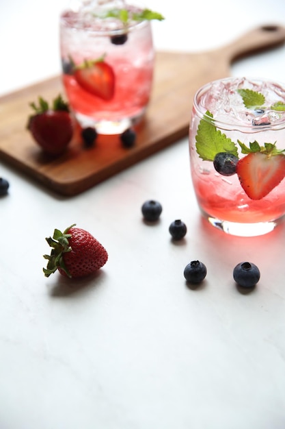 Cocktail de jus de fraise avec glace et menthe sur ton blanc et bois