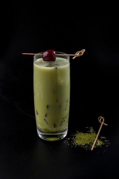 Cocktail laiteux avec brochette de cerise et wasabi sur fond noir