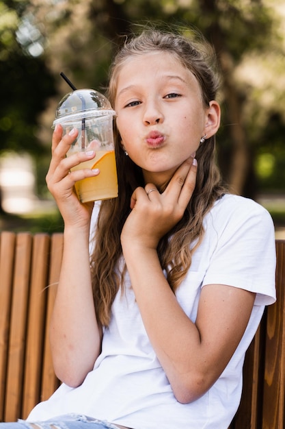 Cocktail de limonade d'été en plein air Bonne fille tenant une tasse avec de la limonade orange et souriant et riant