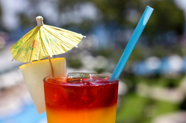 Cocktail lumineux avec parasol sur le fond de la piscine