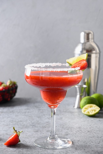 Cocktail margarita aux fraises avec jus de citron vert et glaçon sur fond noir orientation verticale