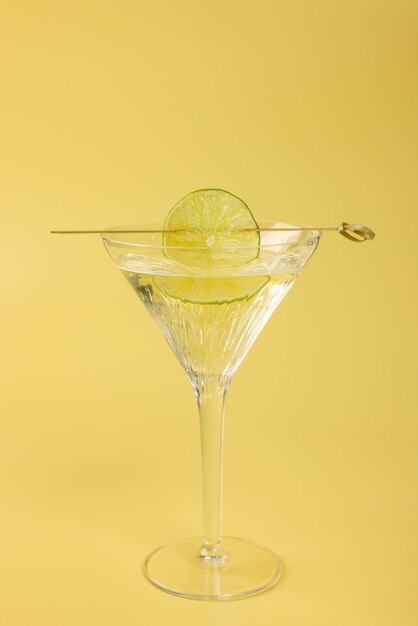 Cocktail Martini avec tranche de citron vert sur fond jaune