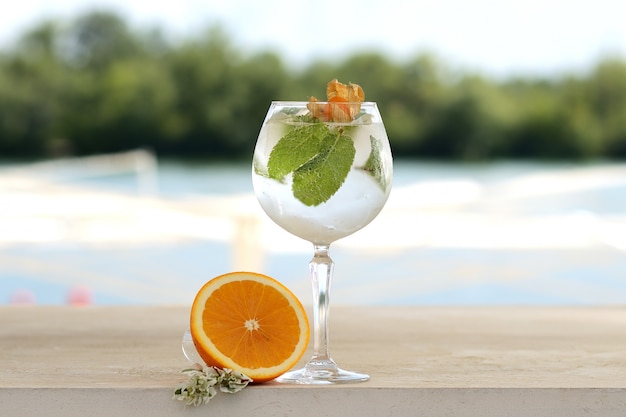 Cocktail à la menthe et glace dans un gobelet en verre. Avec décor de fleurs et de fruits