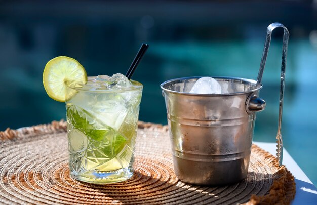 Cocktail mojito blanc avec tranche de citron et seau à glace près de la piscine