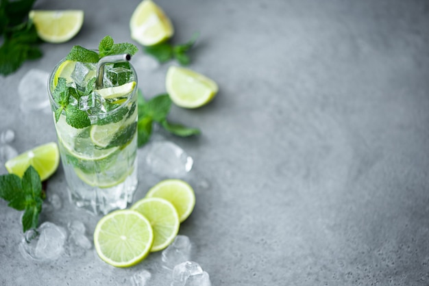 Cocktail Mojito à la menthe, citron vert et glace dans un grand sur fond gris