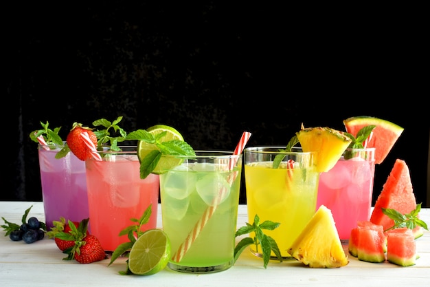 Photo cocktail mojito de plusieurs saveurs tropicales telles que ananas, citron vert, fraise, baies et melon d'eau