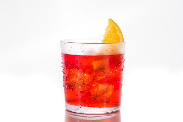 Cocktail Negroni avec morceau d'orange en verre isolé sur blanc