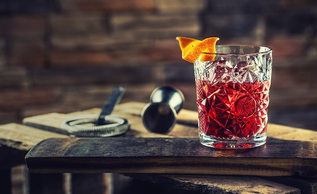 Cocktail Negroni sur une vieille planche de bois. A boire avec du gin, du campari martini rosso et de l'orange.