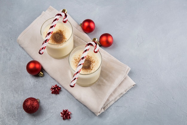 Cocktail de Noël au lait de poule à la cannelle, servi dans deux verres dans des décorations de Noël.