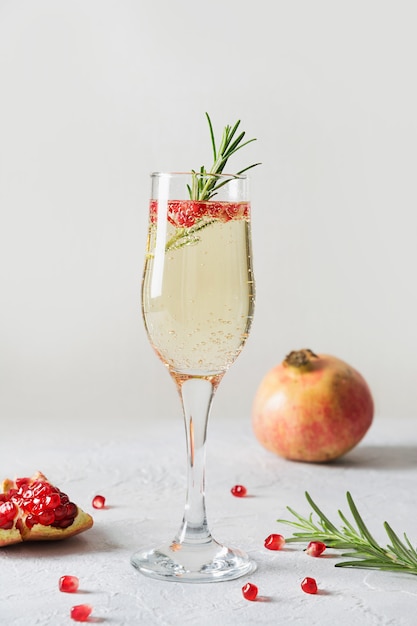 Cocktail de Noël à la grenade au romarin, vin mousseux sur blanc. Boisson de Noël.