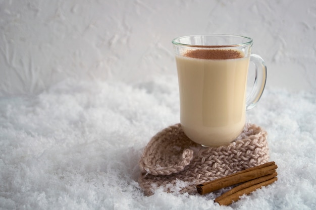 Photo cocktail de noël lait de poule sur un fond clair, dans une tasse en verre.