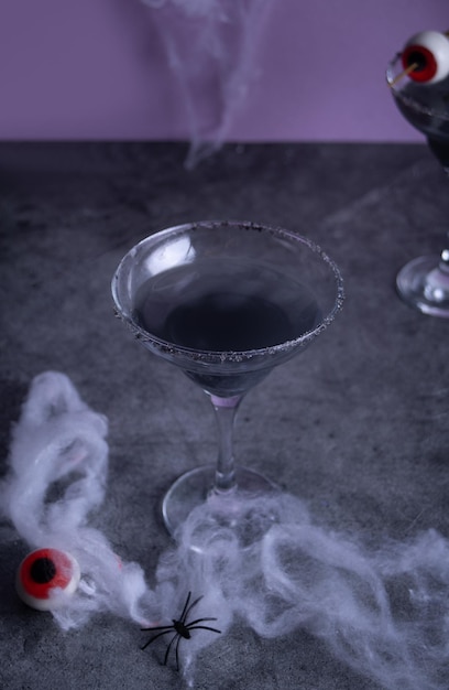 Cocktail noir d'Halloween dans des verres avec un globe oculaire de bonbons Concept de célébration festive