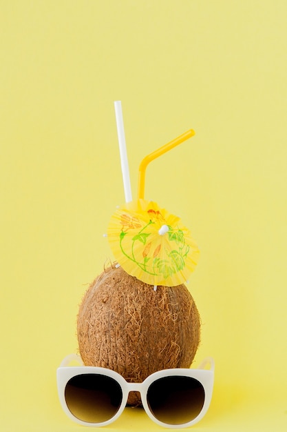 Cocktail de noix de coco fraîche avec une paille sur fond jaune, copiez l'espace.