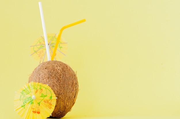 Cocktail de noix de coco fraîche avec une paille sur jaune