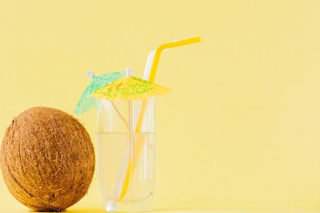 Cocktail de noix de coco fraîche avec une paille sur un mur jaune, espace de copie.