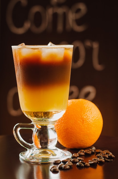 Photo cocktail d'orange froide fraîche avec du café sur la table en bois.