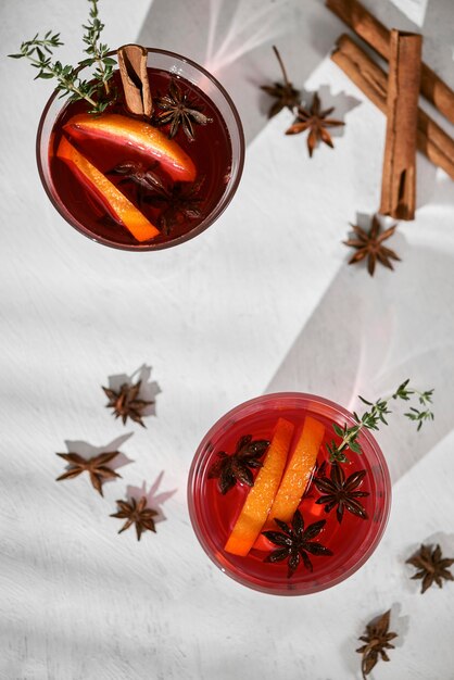 Cocktail orange avec rhum, liqueur, tranches de poire et thym sur table blanche, mise au point sélective