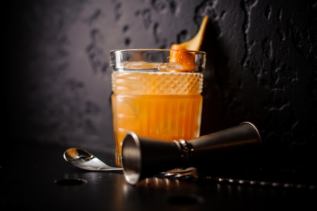 Cocktail orange en verre cristal avec cuillère à bar et jigger