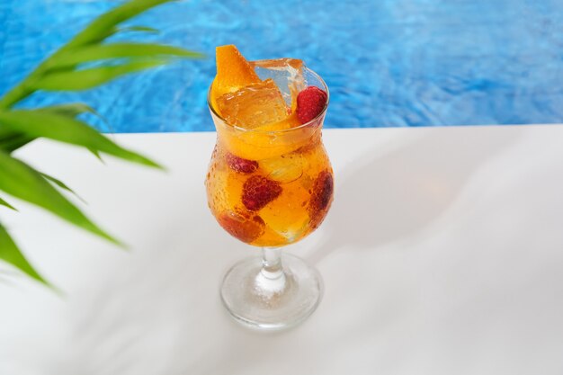 Cocktail orange vif et frais avec framboises et glaçons au bord de la piscine Boisson rafraîchissante tonifiante