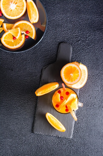 Cocktail pétillant de canneberge orange dans un verre et fruits et baies à proximité sur une ardoise sur fond sombre Mocktail maison Vue de dessus et verticale