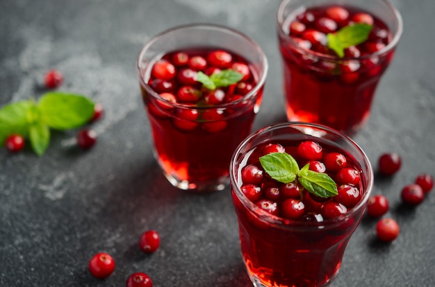 Cocktail rafraîchissant à la canneberge et à la menthe sur du béton foncé.