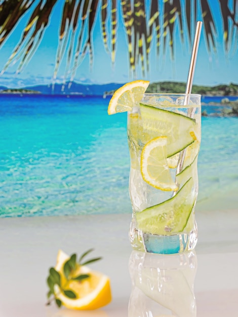 Cocktail réfrigéré au citron et glace sur fond de plage, mer bleue et ciel bleu