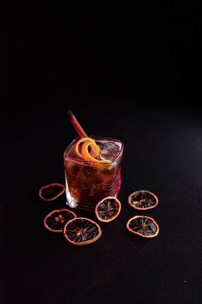 Cocktail de rhum et de cola libre de Cuba dans un verre court à la cannelle et à l'orange Fond noir