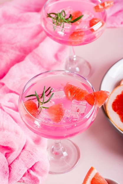 Cocktail rose fait maison avec de la glace et du romarin dans des verres sur la table Vue verticale